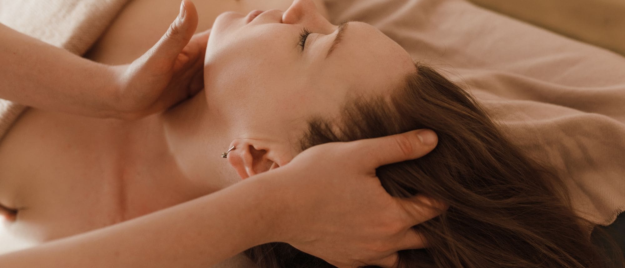 A guest receiving a slow head and neck massage in warm light